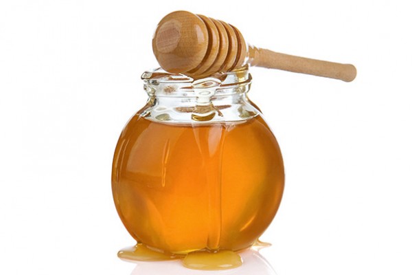 glass jar of honey and stick isolated on white