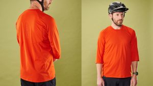Man wearing the orange 7Mesh Optic Shirt 3/4 mountain bike jersey