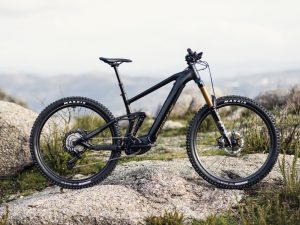 Photo of black Moustache Samedie e-mountain bike on rocks with a landscape view behind