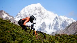 Enduro mountain biker riding with snowcapped mountain in the background