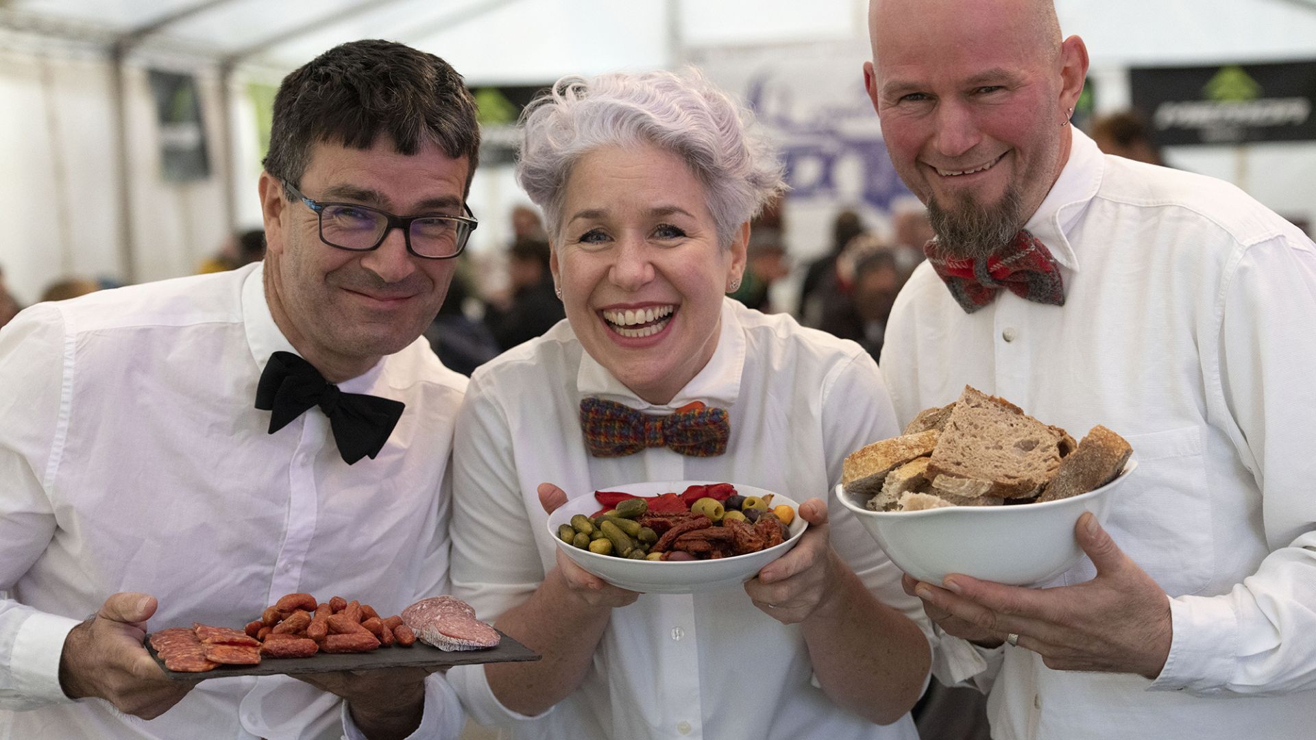 Three smartly dressed caterers with bow ties offer dishes of canepes at the EX Enduro 2022