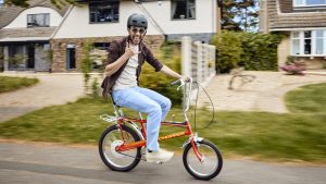Man riding new Raleigh Chopper in red on a residential street