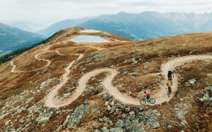 High Alpine singletrack berms, with three riders mountain biking