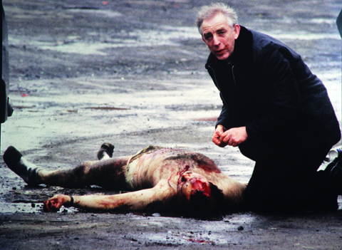 Father Alex Reid gives the last rites to a dying British soldier. Belfast, 1988