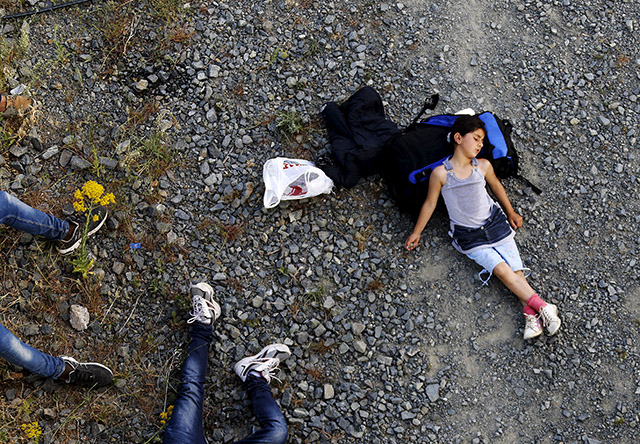 Seven year-old Ariana, a Kurdish-Syrian immigrant, rests before crossing into Macedonia along with another 45 Syrian immigrants near the border Greek village of Idomeni in Kilkis prefecture May 14, 2015. Hundreds of mostly Afghan, Syrian, and African immigrants cross daily from Greece into Macedonia on their way to northern European countries; most of them are turned back by Macedonian border guards. REUTERS/Yannis Behrakis