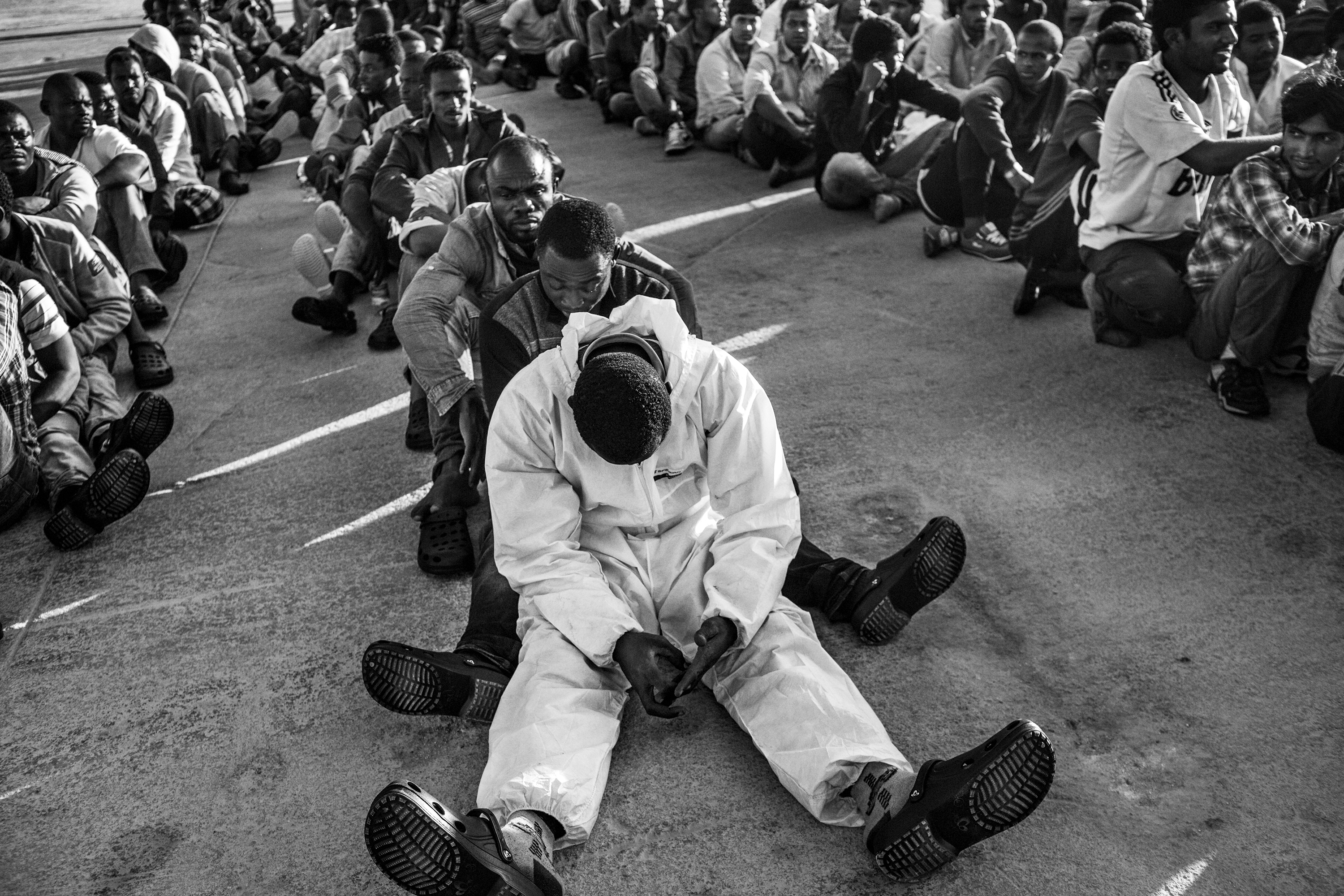 A Sudanese refugee sits on the dock of the Sicilian port of Augusta (Italy) waiting to be transferred to the first reception area, June 23, 2015. He fled from Darfur, Sudan, passing through the Sahara desert to reach Libya and take a boat towards Europe. He is part of a group of 458 people departed from Libya who were saved and disembarked from the Spanish Coast Guard vessel in the Sicilian port of Augusta on June 23, 2015. Among the migrants and refugees were 39 women, 25 minors, 13 of which were unaccompanied. Most of the people came from, Nigeria, Eritrea, Bangladesh, Sudan, Ghana, Somalia, Syria, Palestine. There were also people coming from Ethiopia, Libya, Morocco, Pakistan, Egypt, Tunisia, Togo and Ivory Coast. The number of refugees and migrants taking the dangerous journey across the Mediterranean to Europe, fleeing war, hunger and persecution, is increasing more and more. According to UNHCR's data, more than 1,000,000 arrivals by sea were registered in 2015 in Europe.