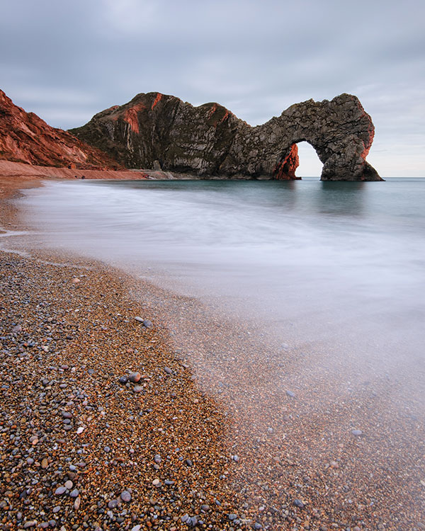 The last of the sunlight illuminates the arch of Durdle Door, Dorset