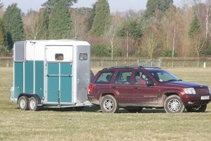 A 4x4 towing a two-horse trailer across a field