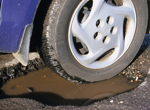 vehicle wheel in pothole on road uk