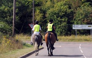 C7H3AN Two young horse riders riding on a main road at a road junction