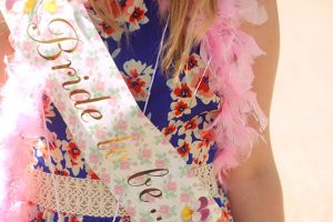 EFBKX7 A bride to be wearing a hen party sash and feather boa