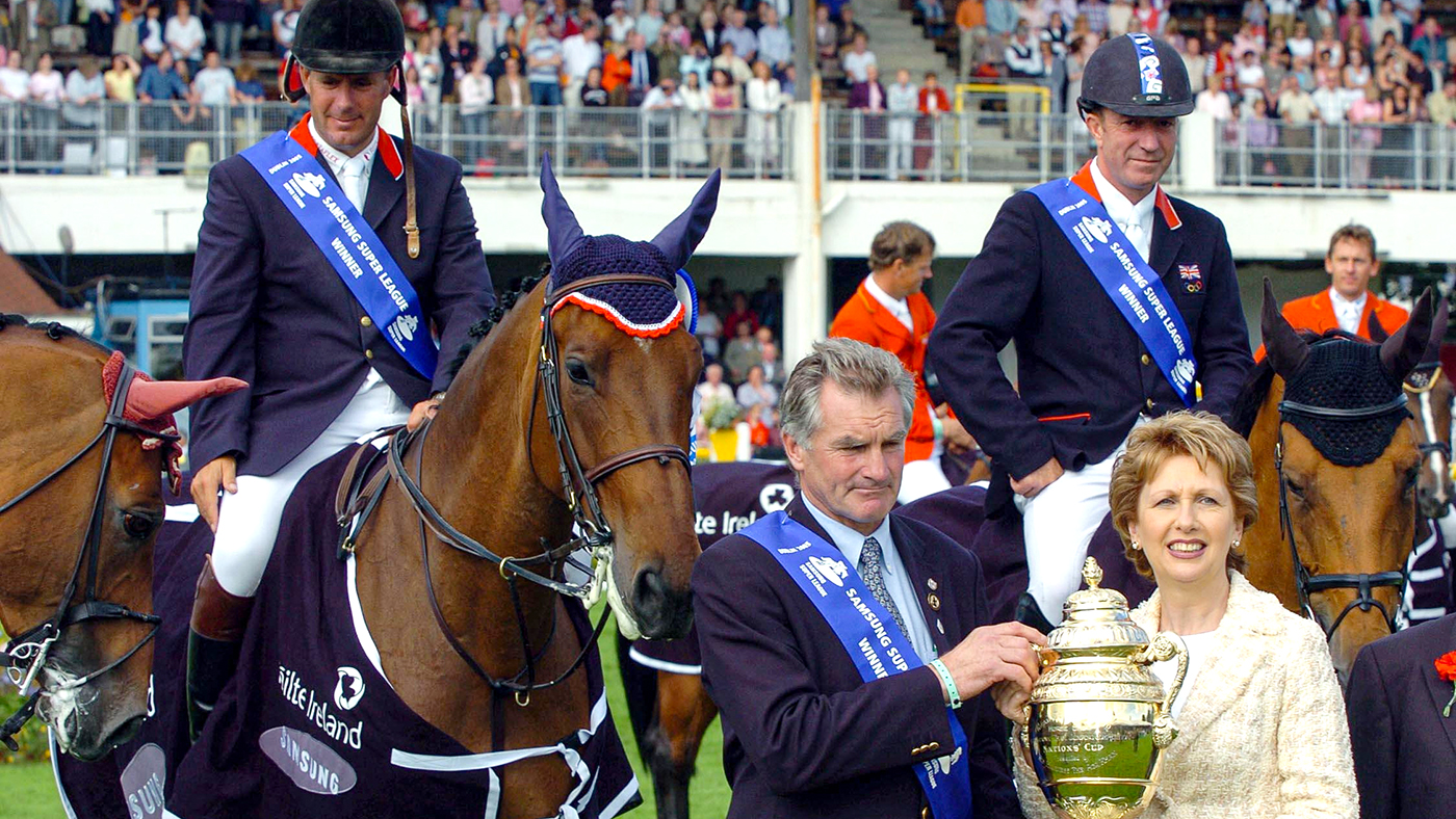 Great Britain's Chef d'Equipe, Derek Ricketts accepts the Aga Khan Challenge Trophy from President Mary McAleese as riders William Funnel on Cortaflex Mondriaan (left) and Michael Whitaker on Portofino 63 (right) look on at the Failte Ireland Dublin Horse Show, Friday August 5 2005, at the Royal Dublin Society Arena, Dublin.