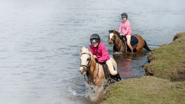 CNKKBW Pony riders crossing the River Ewenny at Ogmore in the Vale of Glamorgan S Wales UK. Image shot 04/2012. Exact date unknown.
