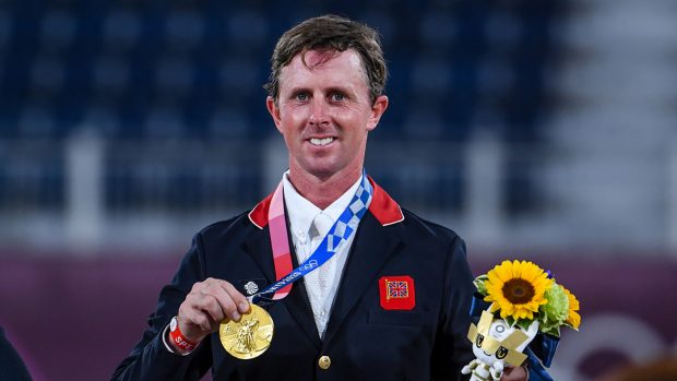 Ben Maher holds up his gold medal after winning the Olympic showjumping individual final