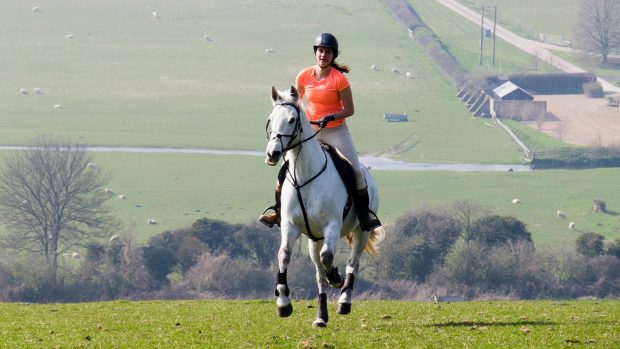 Lady riding in a bright orange summer riding top
