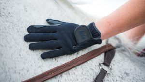 A pair of the best children’s riding gloves worn by model on a horse