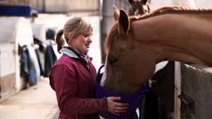 Girl feeding an older horse from a bucket