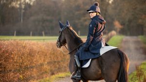 Rider on horse wearing LeMieux Amelie long waterproof riding coat