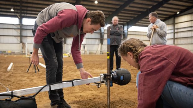 Image shows researchers testing a riding helmet in an arena.