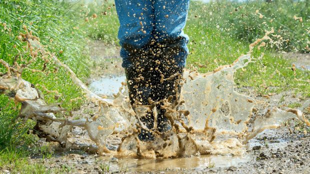 Man wearing wellington boots jumping in puddle