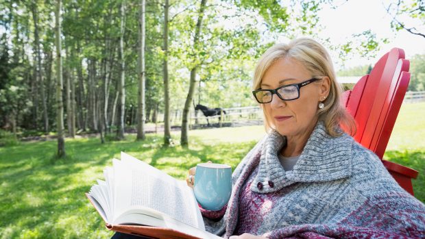 Woman reading an equestrian biography with a horse in the background