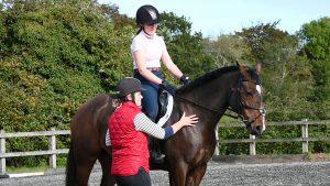 Instructor giving horse rider tips from the ground