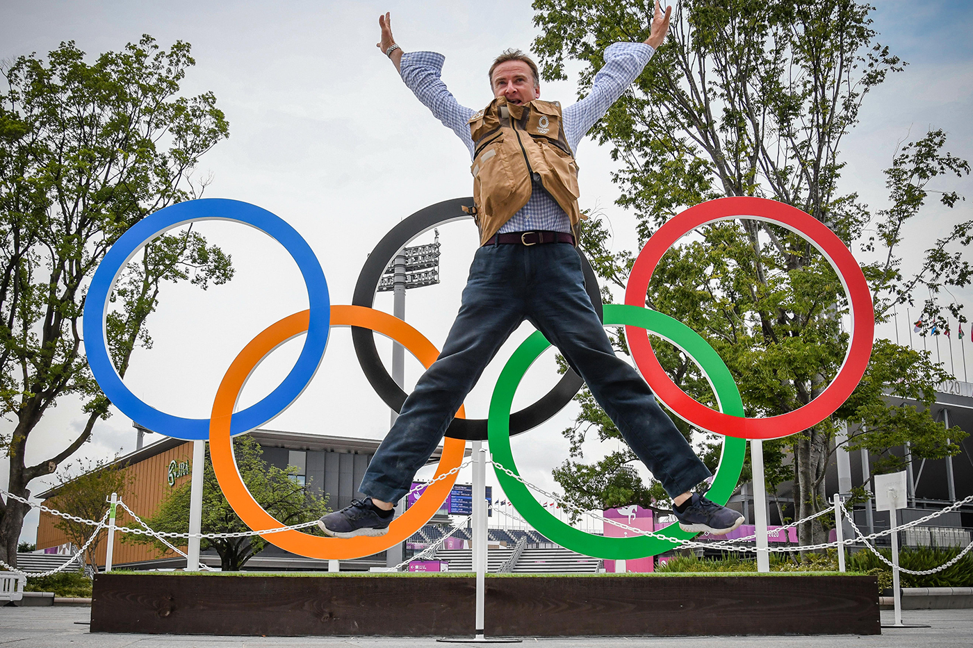 Peter Nixon leaping in the air in front of the Olympic rings in Tokyo