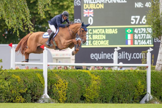 William Funnell clears the private hedge on the Hickstead Derby course riding his chestnut horse Dublon