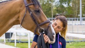 A groom at the 2023 European Showjumping Championships kisses a relaxed horse on the nose
