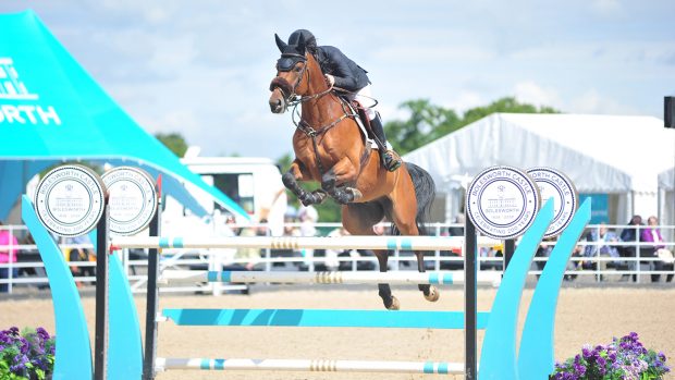 Shane Breen and Be Golden jumping a turquoise blue and white jump at Bolesworth 2024