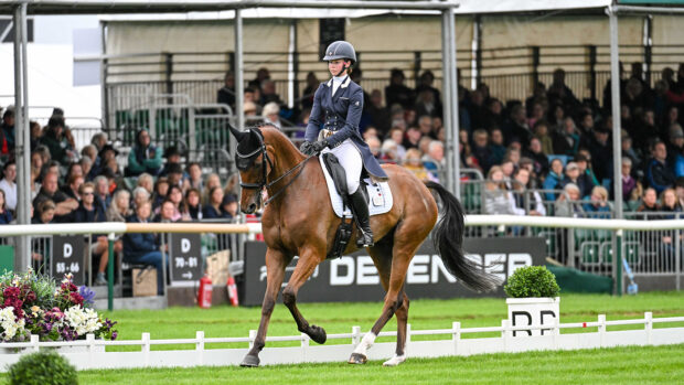 Lizzie Baugh and B Exclusive canter in front of the stands during their Defender Burghley Horse Trials dressage test.