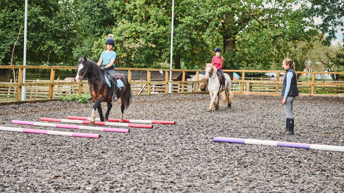 two young girls having a lesson in an arena