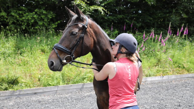 Rider looking at her horse and scratching withers