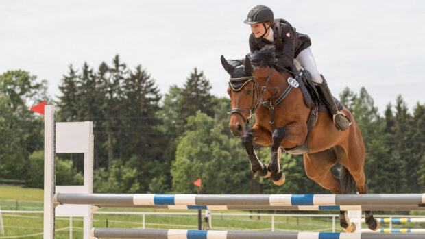 Smiling girl jumping horse, looking full of confidence