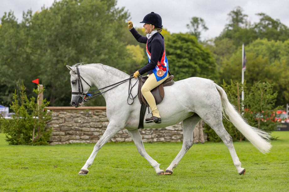 Samantha Taylor waves her hand as Waxwing Perlina shows off her delightful trot in Hickstead’s international arena at the Agria Royal International Horse Show.