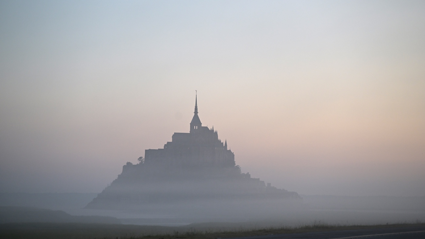 This photograph shows the Mont-Saint-Michel in northwestern France, enveloped in the early morning mist, on July 9, 2025. (Photo by Damien MEYER / AFP)