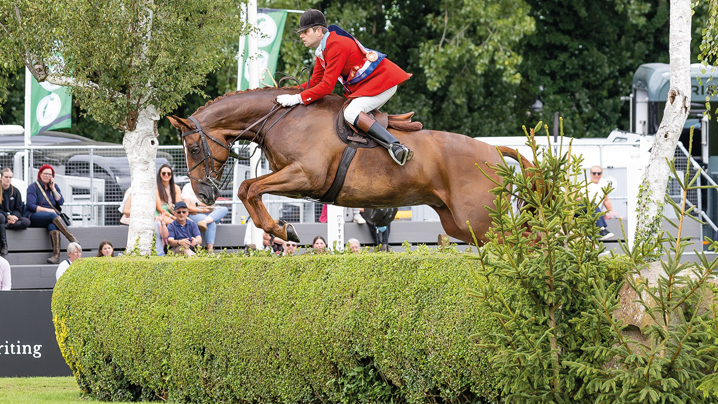 Craig Kiddier and Mulberry Lane clear a hedge in Hickstead's international arena while wearing their champion’s sash