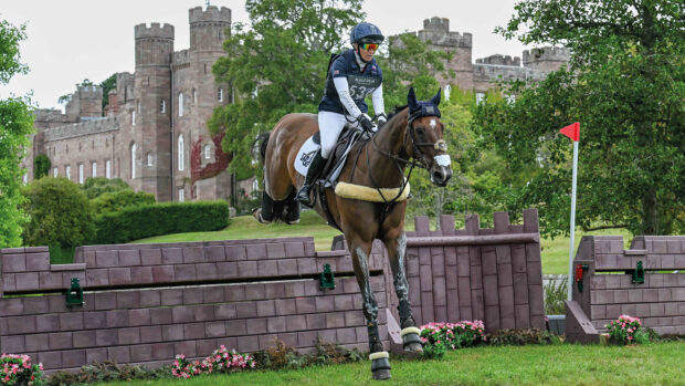 Laura Collett and London 52 clear a castle-shaped cross-country fence with Scone Palace in the background.