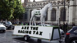 LONDON, ENGLAND - SEPTEMBER 10: A model race horse with the statement "#Axe the racing tax" is displayed outside the Houses of Parliament on September 10, 2025 in London, England. British Racing has cancelled all horse racing meets tomorrow in support of the 'Axe The Race Tax' movement hoping to persuade the government not to include horse racing betting in their gambling tax simplification plans. Jockeys including Hollie Doyle, Tom Marquand, Saffie Osborne, Kieran Shoemark, Lily Pinchin, Richard Johnson, Oisin Murphy, Harry Cobden and Paul O'Brien were to take part. (Photo by Dan Kitwood/Getty Images)