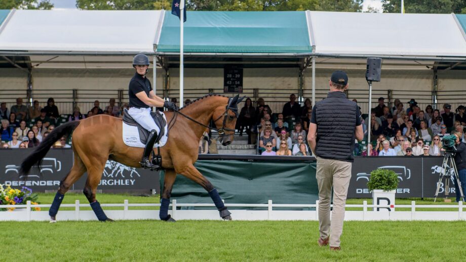Tom McEwen rides Toledo De Kerser in front of the Burghley crowds with Carl Hester looking on