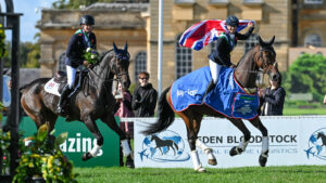 Bronze medallists JL Dublin ridden by Tom McEwen (left) and individual gold medalist Laura Collett holds the union flag aloft on board London 52, who is wearing his winners rug on their lap of honour in front of Blenheim Palace.
