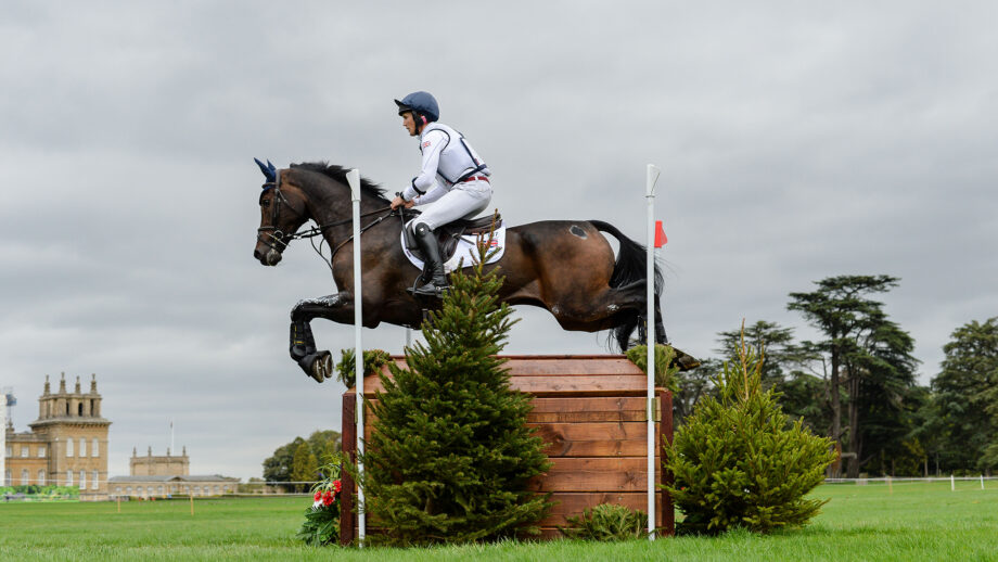 XXX medallist Tom McEwen clears a large wooden chest riding JL Dublin on the 2025 European Eventing Championships cross-country course with a wing of Blenheim Palace in the background