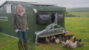 Jeremy Clarkson stands in front of a chicken coop on his farm.