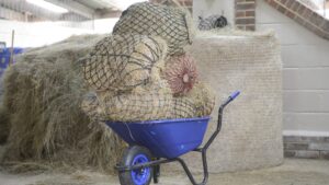 Wheelbarrow piled up with large haynets