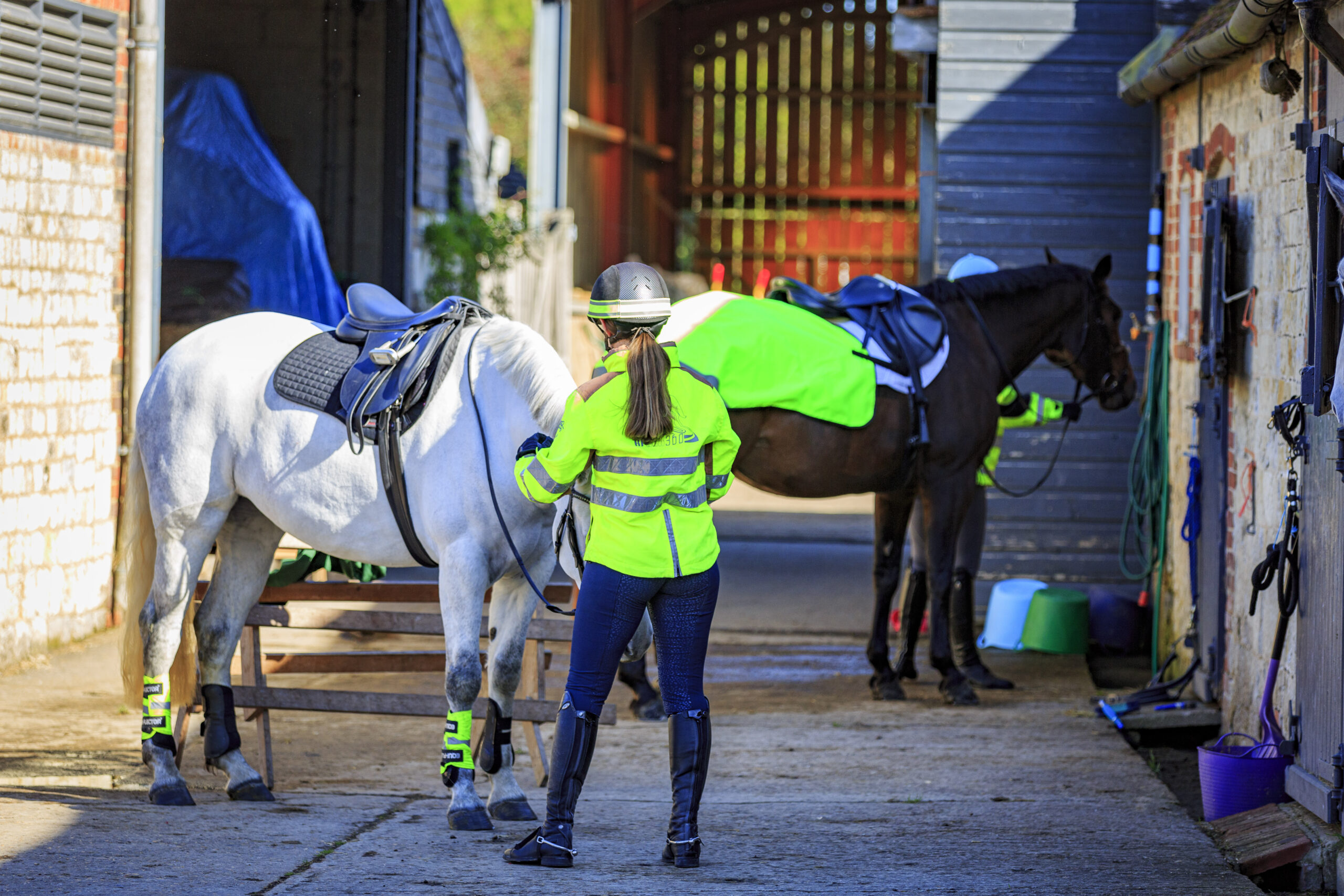 Horse riders preparing to leave the yard in hi-vis in winter
