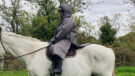 Lady wearing Hestt Eco-Ultra Riding Robe with hood up on horse side view