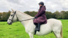 Rider wears LeMieux All Elements riding robe on horse, viewed from the side