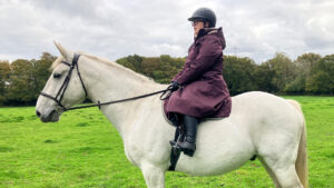 Rider wears LeMieux All Elements riding robe on horse side view