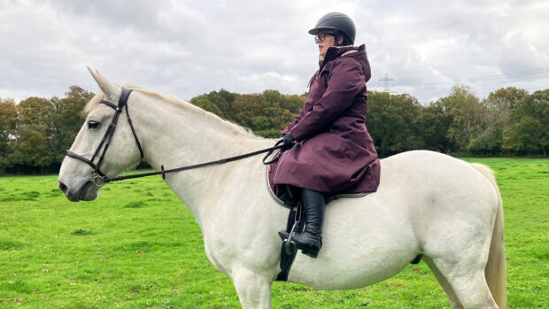 Rider wears LeMieux All Elements riding robe on horse, viewed from the side
