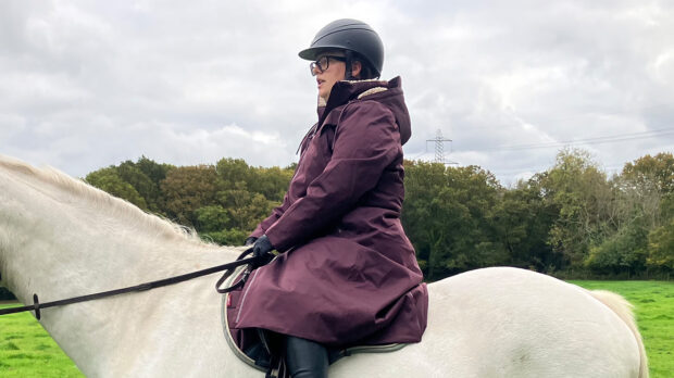 Rider wears LeMieux All Elements riding robe on horse, viewed from the side